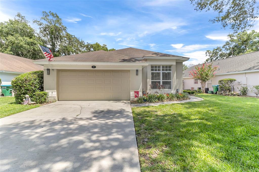 A single-story house with a beige garage, a concrete driveway, and a front lawn — 661 ANDOVER CIRCLE, WINTER SPRINGS, FL
