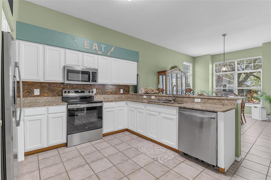 A kitchen with white cabinets, granite countertops, stainless steel appliances, and light green walls — 661 ANDOVER CIRCLE, WINTER SPRINGS, FL