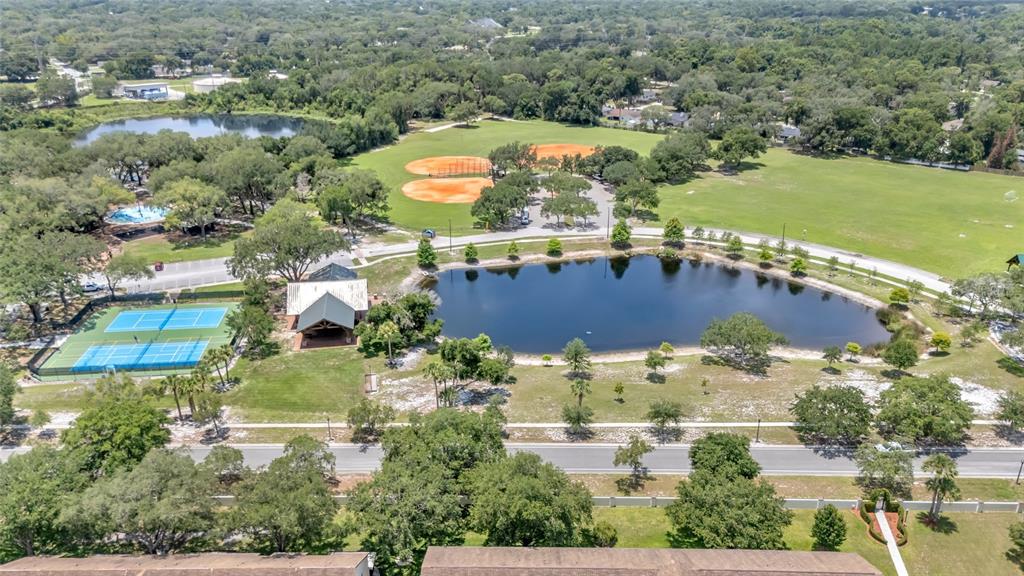 An aerial view shows a park with a pond, tennis courts, and baseball fields — 661 ANDOVER CIRCLE, WINTER SPRINGS, FL
