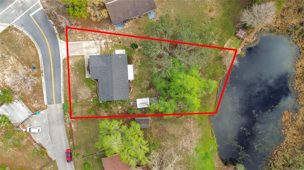 An aerial view shows a house with a driveway and large trees beside a pond — 1975 N SCENIC WAY, CRYSTAL RIVER, FL