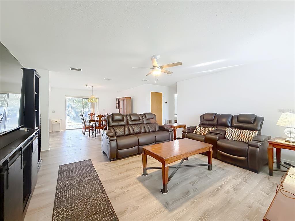A living room with wood-look flooring, brown leather furniture, and an adjacent dining area — 1975 N SCENIC WAY, CRYSTAL RIVER, FL