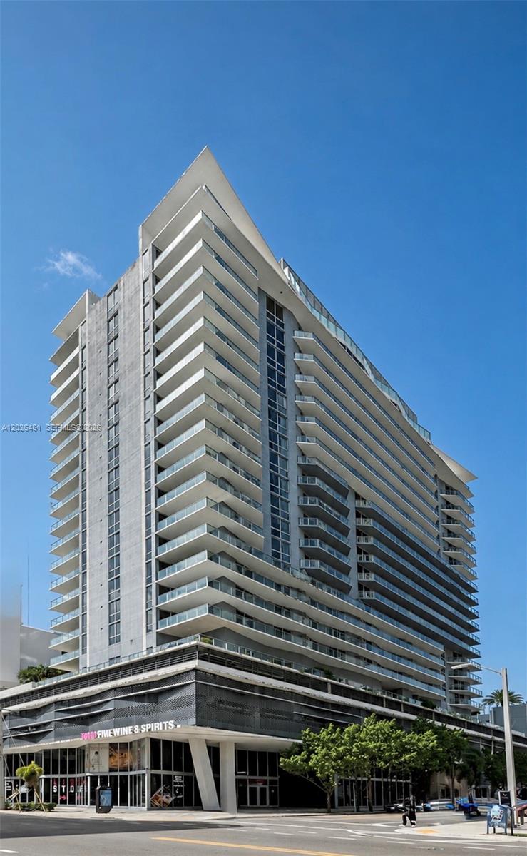 A low-angle exterior view of a modern high-rise residential building with stacked glass balconies — 1010 SW 2nd Ave # 809, Miami FL 33130, MIAMI, FL