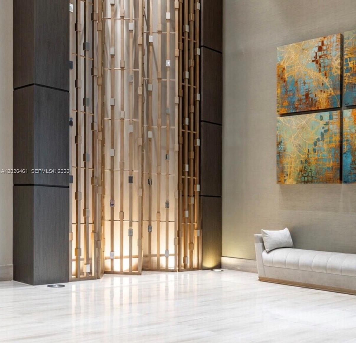 A modern lobby features a decorative wooden screen, marble flooring, a bench, and abstract art — 1010 SW 2nd Ave # 809, Miami FL 33130, MIAMI, FL