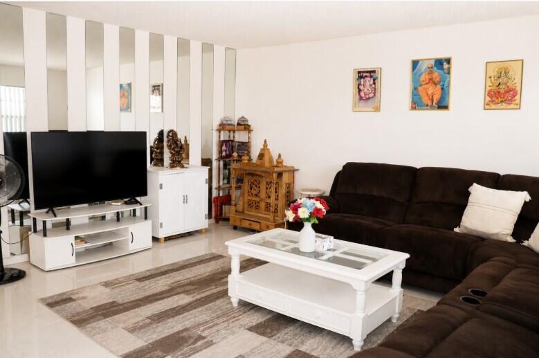 A living room featuring a brown sectional sofa, white coffee table, television, and wooden shrine — 321 Burgundy G, Delray Beach FL 33484, DELRAY BEACH, FL