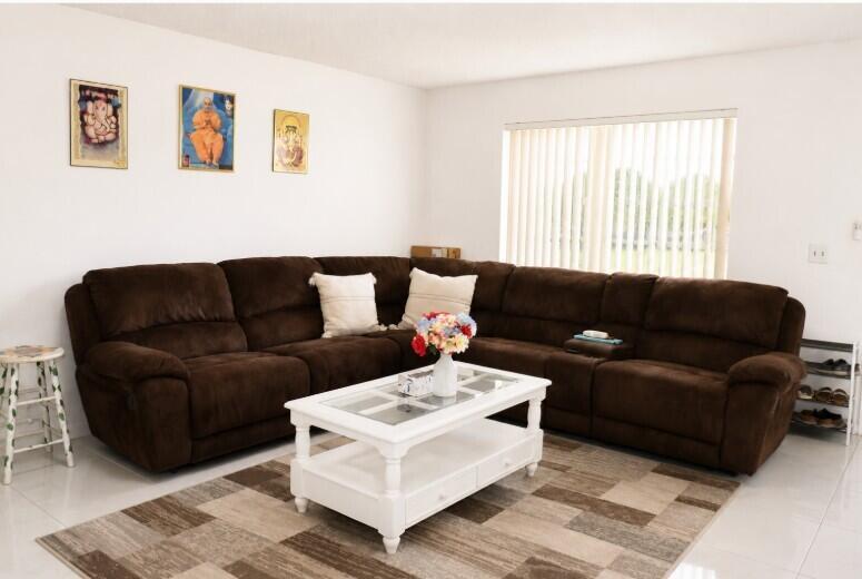 A living room features a large brown sectional sofa, a white coffee table, and artwork — 321 Burgundy G, Delray Beach FL 33484, DELRAY BEACH, FL