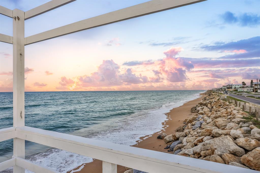 A view of the ocean and rocky shoreline from a white wooden balcony at sunset — 1204 S OCEAN SHORE BOULEVARD, FLAGLER BEACH, FL