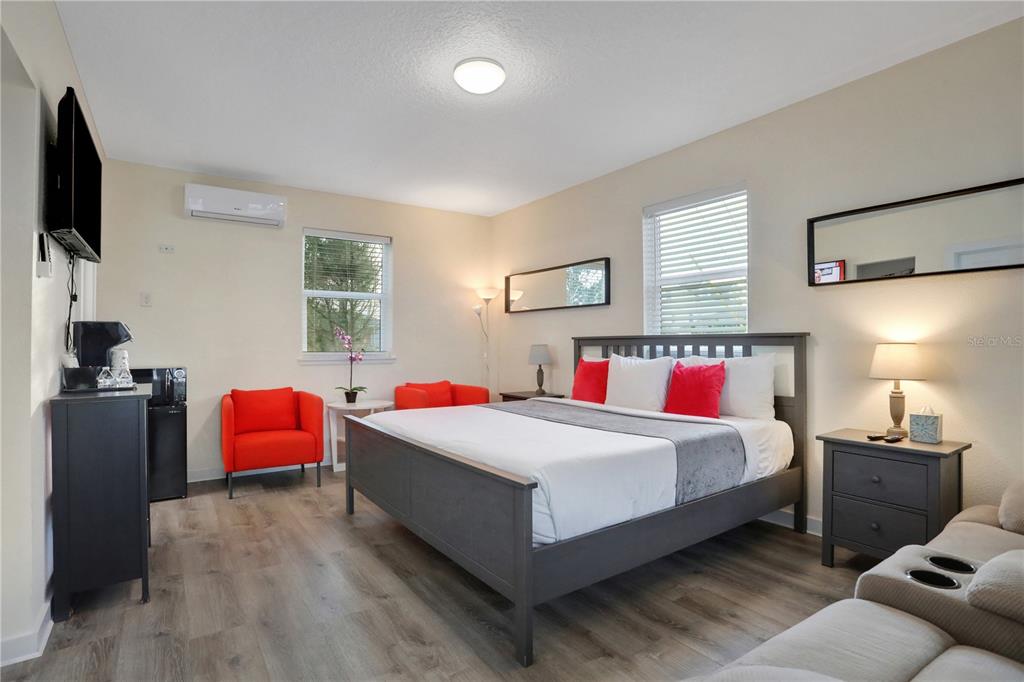A bedroom features a gray bed frame, two red armchairs, and light wood-look flooring — 1204 S OCEAN SHORE BOULEVARD, FLAGLER BEACH, FL