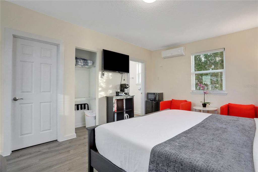 A bedroom features a bed, two red armchairs, a television, and a small kitchenette area — 1204 S OCEAN SHORE BOULEVARD, FLAGLER BEACH, FL