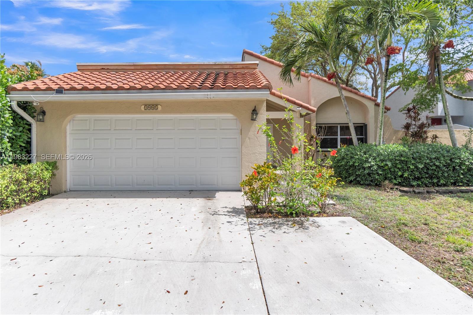 The exterior of a single-story house features a two-car garage, stucco walls, and tile roof — 2905 Begonia Way, Cooper City FL 33026, COOPER CITY, FL