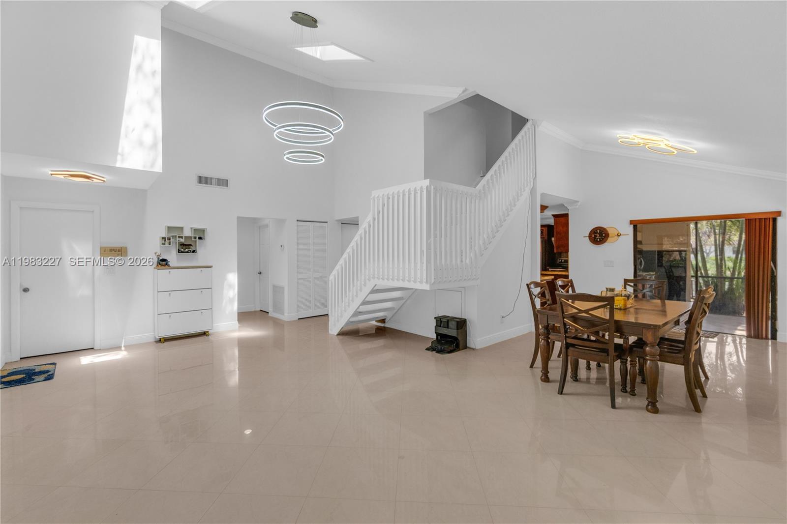 A bright, open-concept dining area features a staircase, tile flooring, and modern light fixtures — 2905 Begonia Way, Cooper City FL 33026, COOPER CITY, FL
