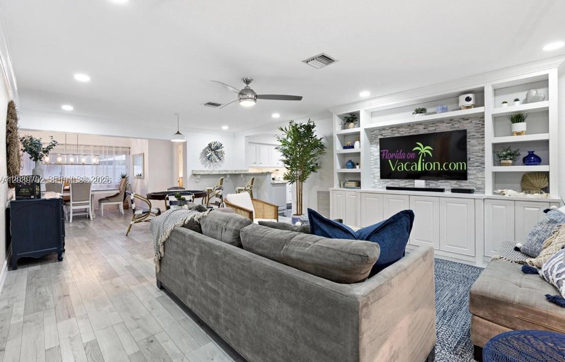 A living room features a large gray sectional sofa, built-in shelving, and light wood flooring — 2580 SE 2nd Ct, Pompano Beach FL 33062, POMPANO BEACH, FL