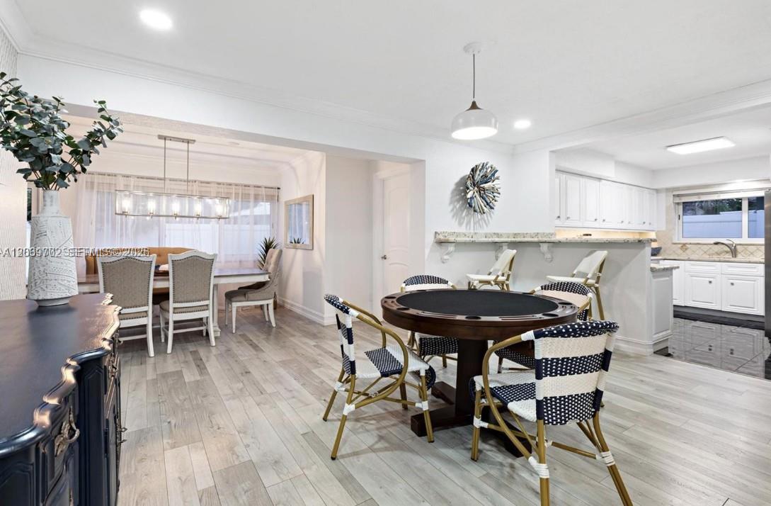 A dining area and kitchen feature a game table, white cabinetry, and light wood flooring — 2580 SE 2nd Ct, Pompano Beach FL 33062, POMPANO BEACH, FL