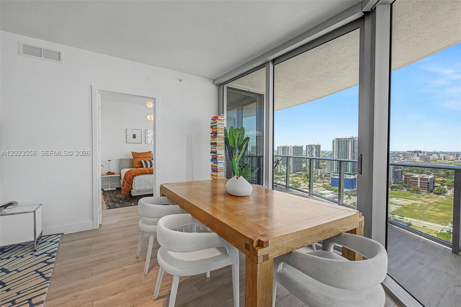 A dining area with a wooden table and white chairs overlooks a city skyline — 488 NE 18th St # 3101, Miami FL 33132, MIAMI, FL