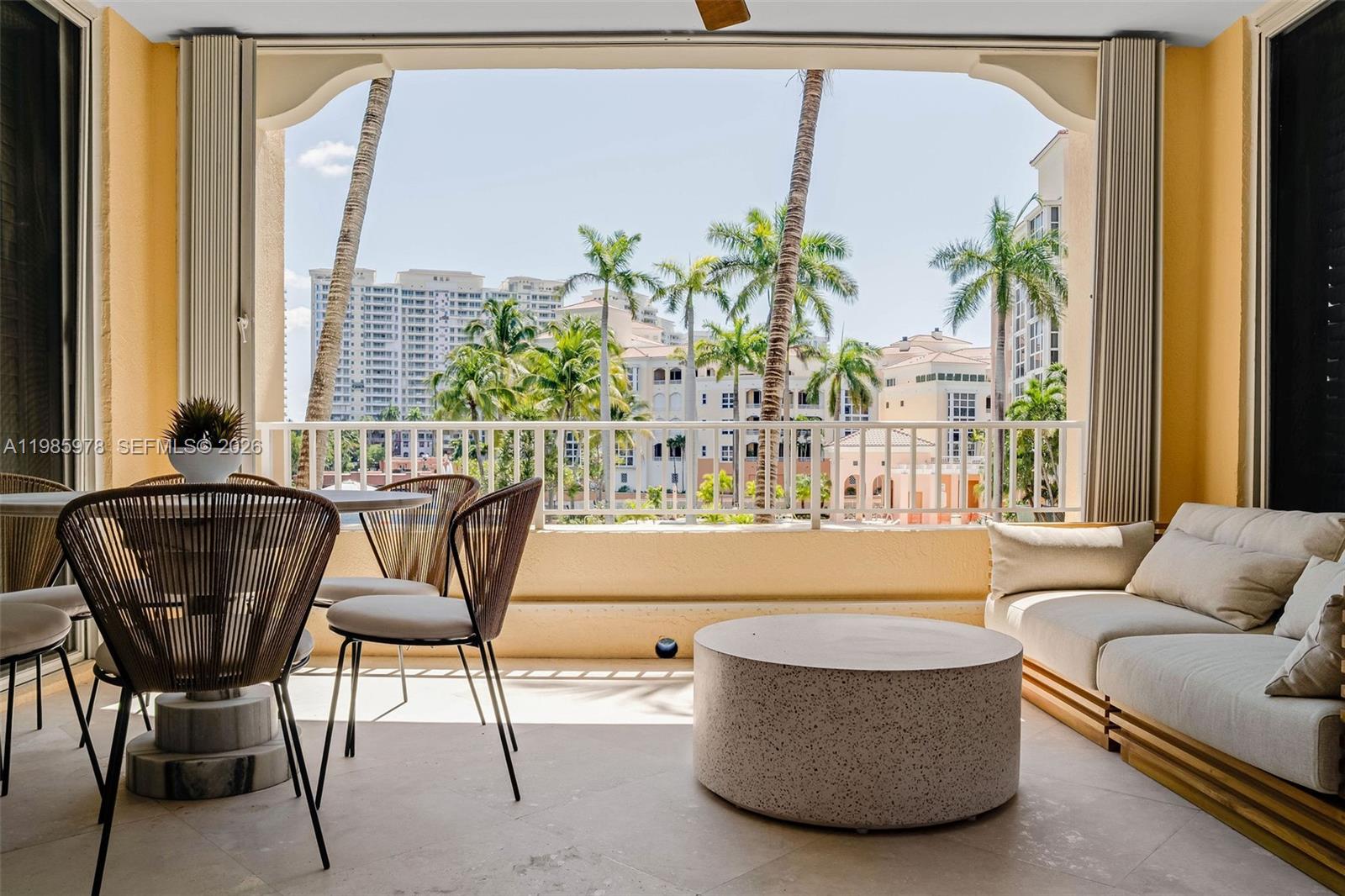 A covered balcony features a dining set, a low coffee table, and a cushioned sofa — 725 Crandon Blvd # 203, Key Biscayne FL 33149, KEY BISCAYNE, FL
