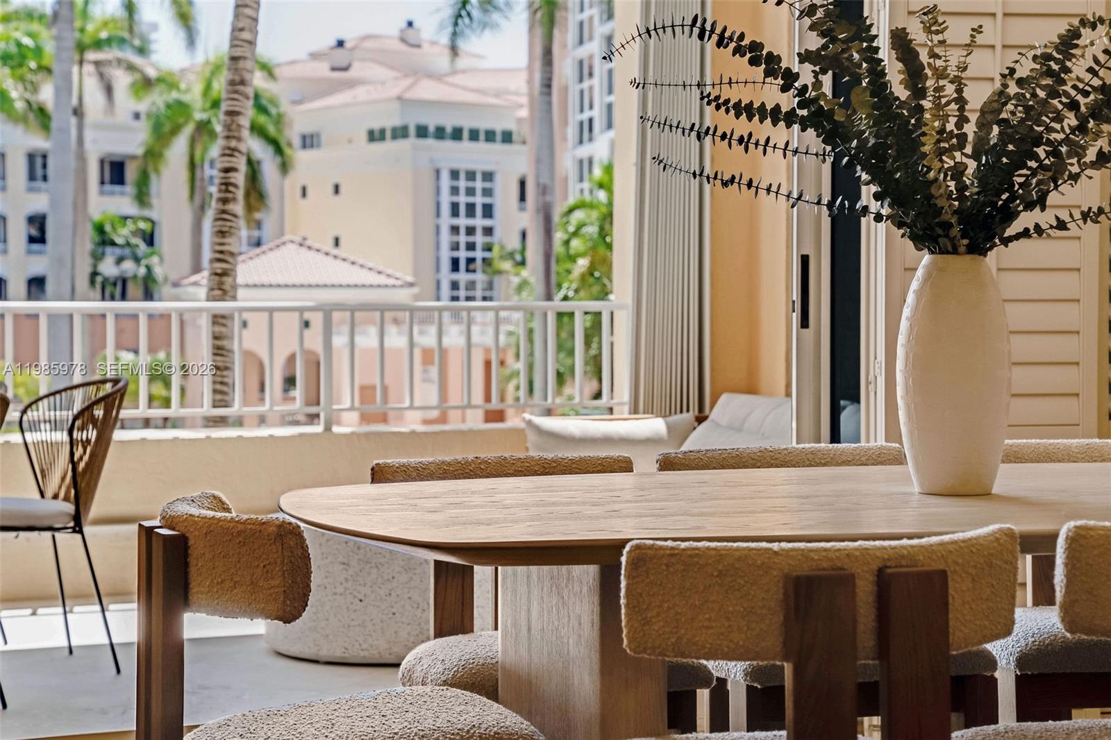 A dining area features a wooden table with textured chairs and a balcony view — 725 Crandon Blvd # 203, Key Biscayne FL 33149, KEY BISCAYNE, FL