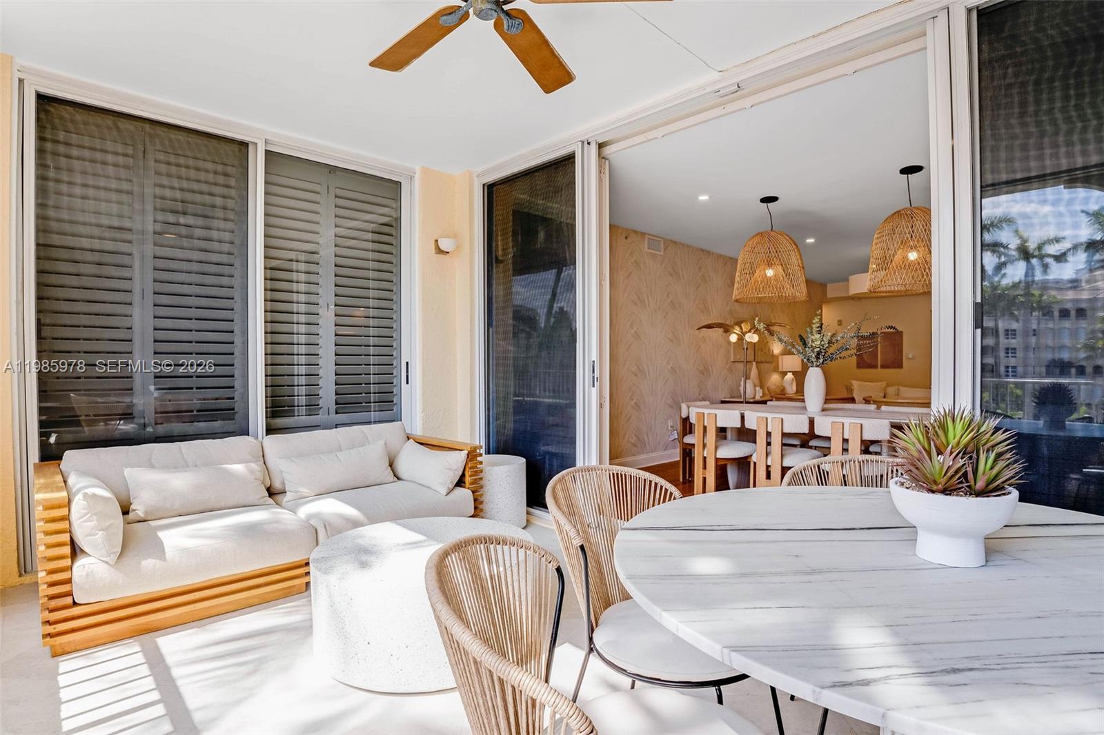A covered balcony features a sofa, a round table with chairs, and sliding glass doors — 725 Crandon Blvd # 203, Key Biscayne FL 33149, KEY BISCAYNE, FL
