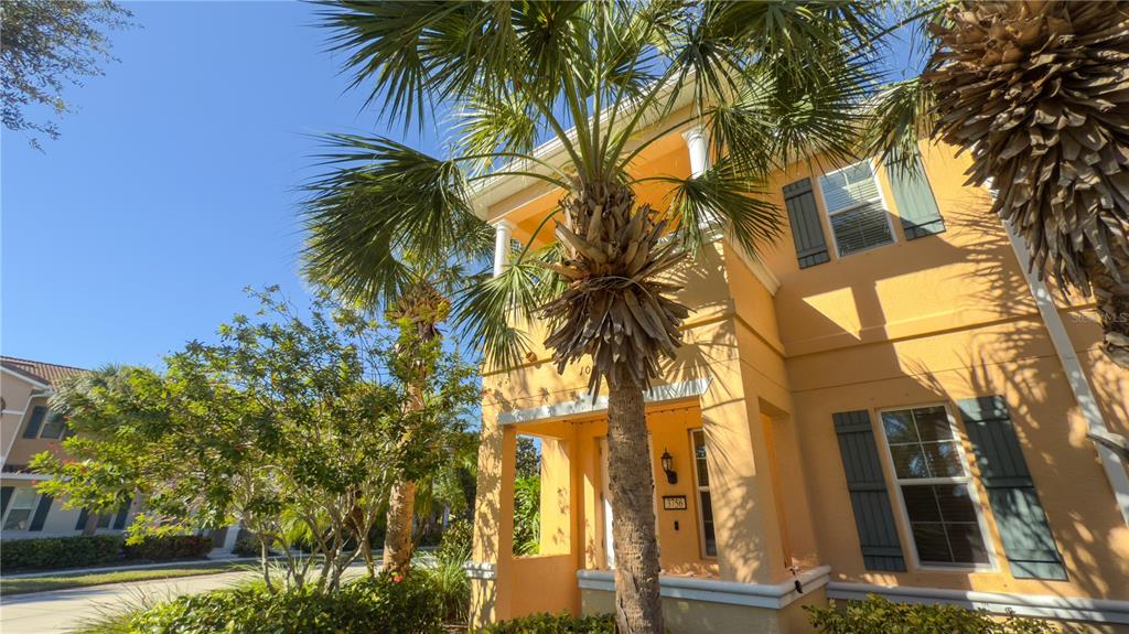 A two-story yellow house with a covered front porch and palm trees in the yard — 3756 82ND AVENUE CIRCLE E UNIT 101, SARASOTA, FL
