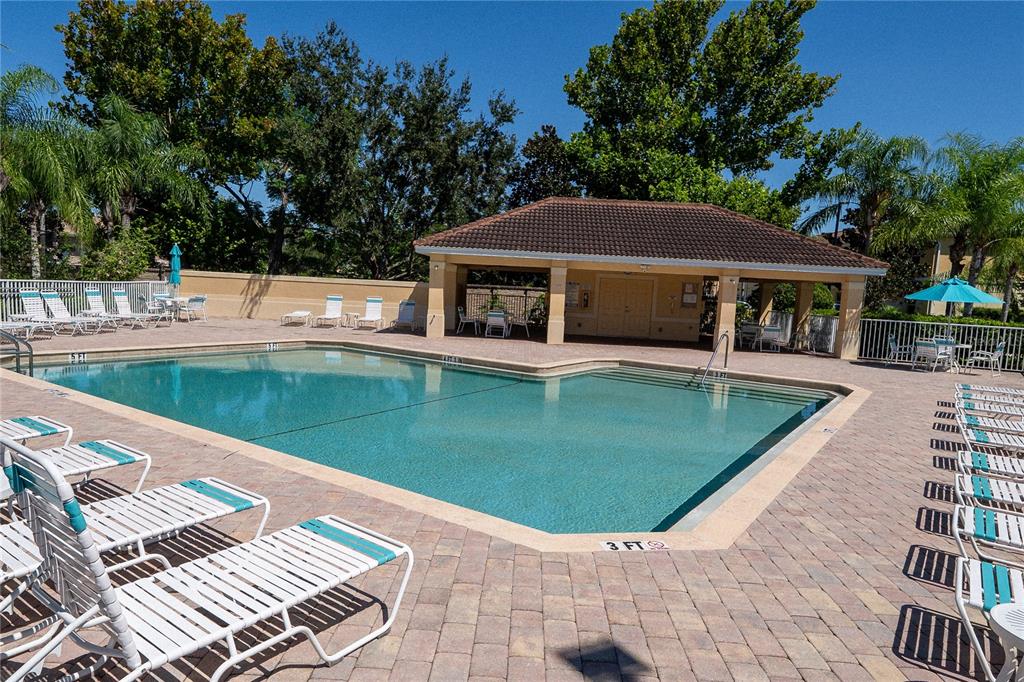 An outdoor swimming pool with lounge chairs and a covered pavilion on a brick patio — 3756 82ND AVENUE CIRCLE E UNIT 101, SARASOTA, FL