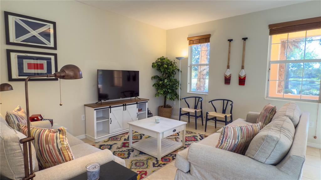 A living room features two sofas, a white media console, and a patterned area rug — 3756 82ND AVENUE CIRCLE E UNIT 101, SARASOTA, FL