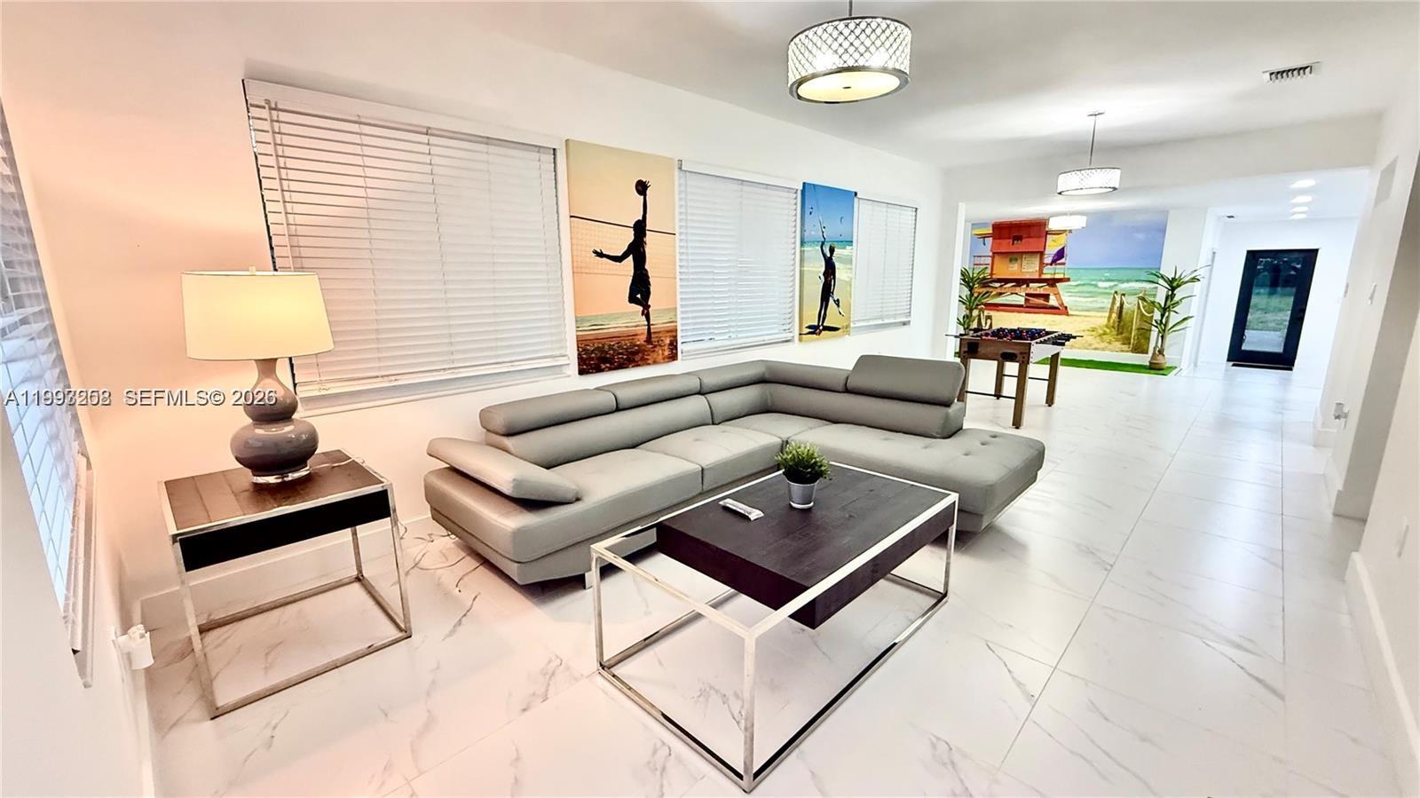 A living room features a gray sectional sofa, a coffee table, and beach-themed wall art — 5401 W Broward Blvd, Plantation FL 33317, PLANTATION, FL
