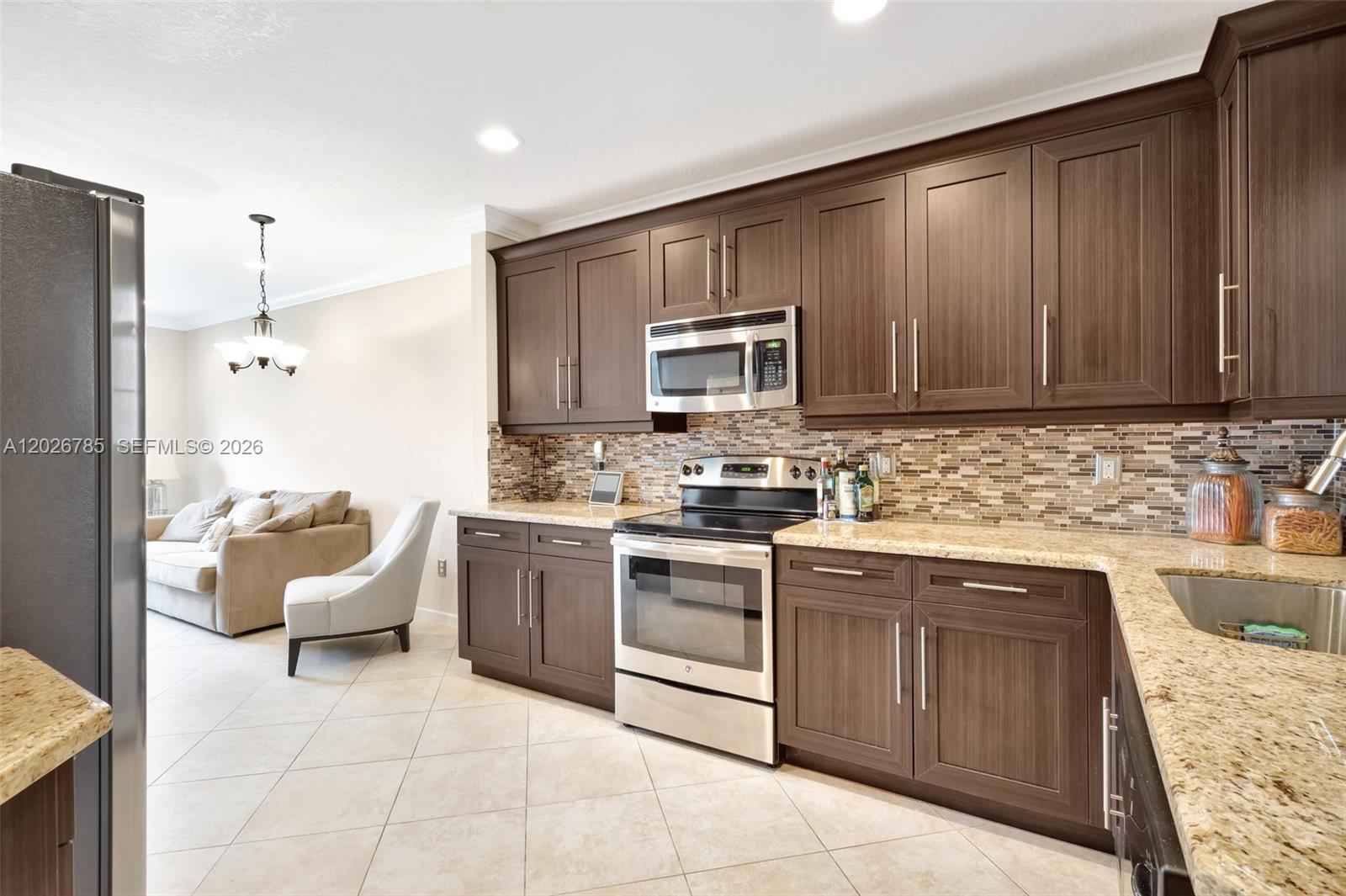 A kitchen features dark wood cabinets, granite countertops, stainless steel appliances, and a tiled backsplash — 4302 Colony View Dr, Lake Worth FL 33463, LAKE WORTH, FL