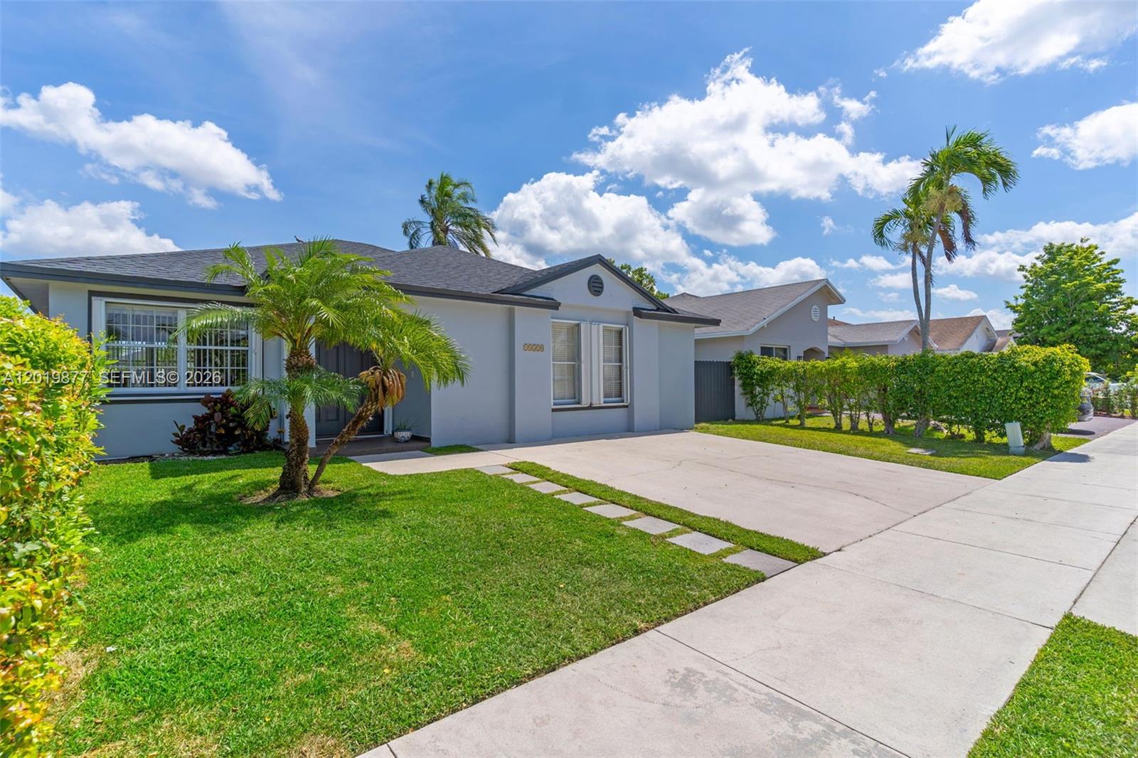 A single-story house with a gray exterior, a concrete driveway, and a small palm tree — 13520 SW 180th Ter, Miami FL 33177, MIAMI, FL