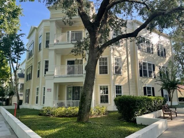 A three-story yellow apartment building features white balconies and a large tree in front — 460 WATER STREET UNIT 460, CELEBRATION, FL