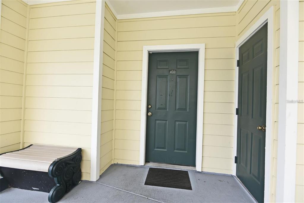 A porch with yellow horizontal siding, a dark green front door, and a storage closet — 460 WATER STREET UNIT 460, CELEBRATION, FL
