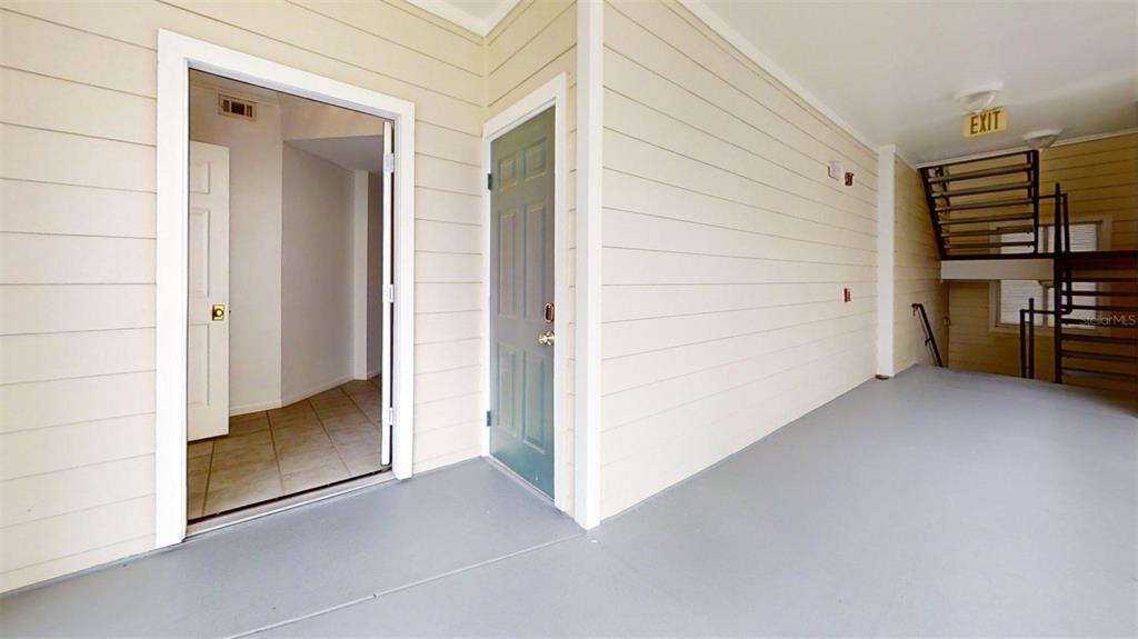 An outdoor covered walkway features a doorway, a utility door, and a metal staircase — 460 WATER STREET UNIT 460, CELEBRATION, FL