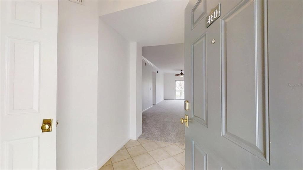 An open door reveals an entryway with tile flooring leading into a carpeted living area — 460 WATER STREET UNIT 460, CELEBRATION, FL