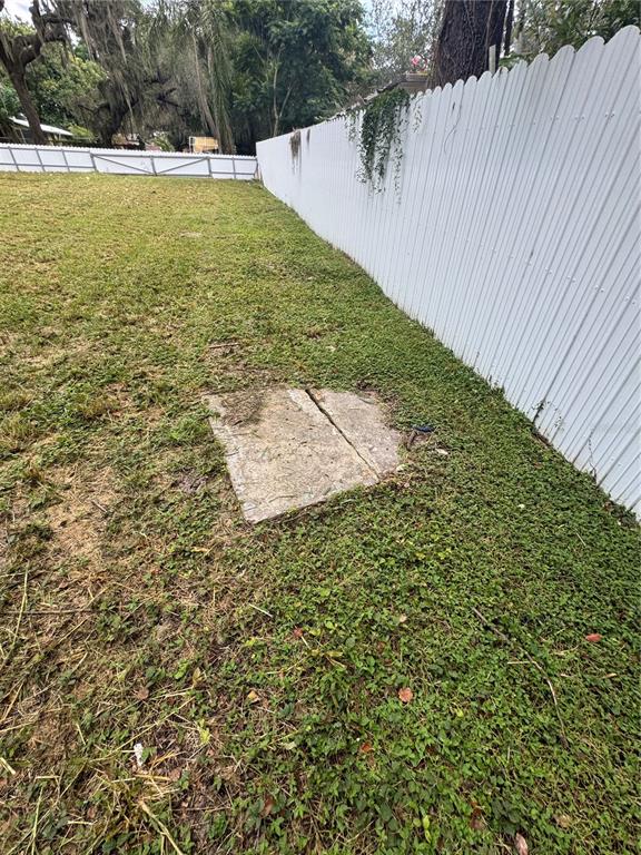 A concrete slab sits in a grassy backyard next to a white vinyl fence — 2211 KEUKA AVENUE, LEESBURG, FL