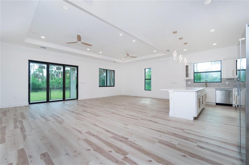 An open-concept living room and kitchen featuring white walls, light wood flooring, and recessed lighting — 289 ALBATROSS ROAD, ROTONDA WEST, FL