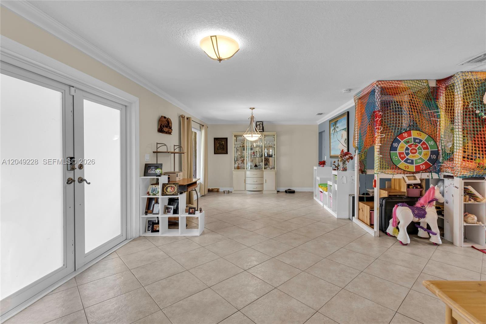 A spacious, tiled living area features a glass door, a china cabinet, and a play area — 16740 Harbor Ct, Weston FL 33326, WESTON, FL