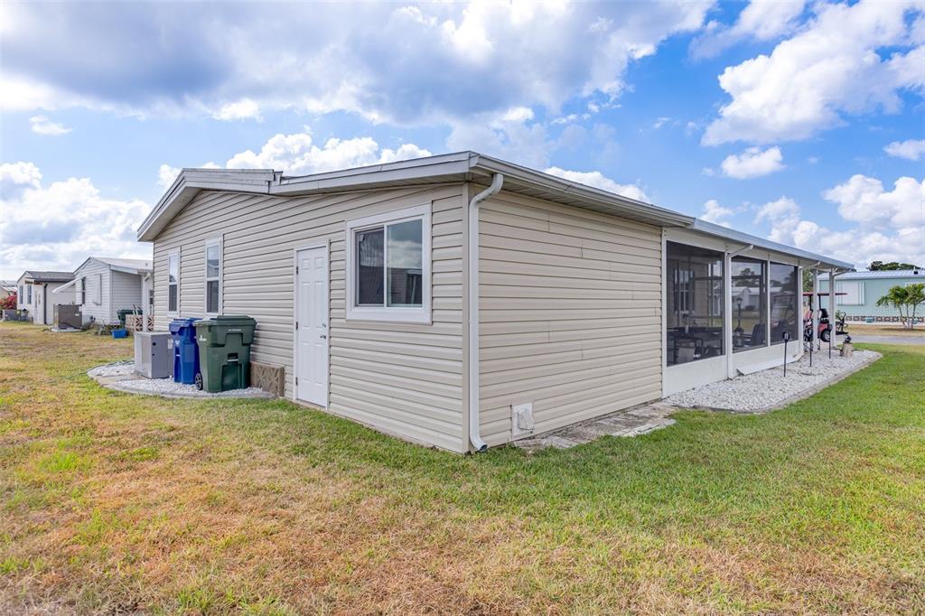 A beige manufactured home features a side entrance, a screened-in porch, and two trash bins — 622 LA SALA, NORTH PORT, FL