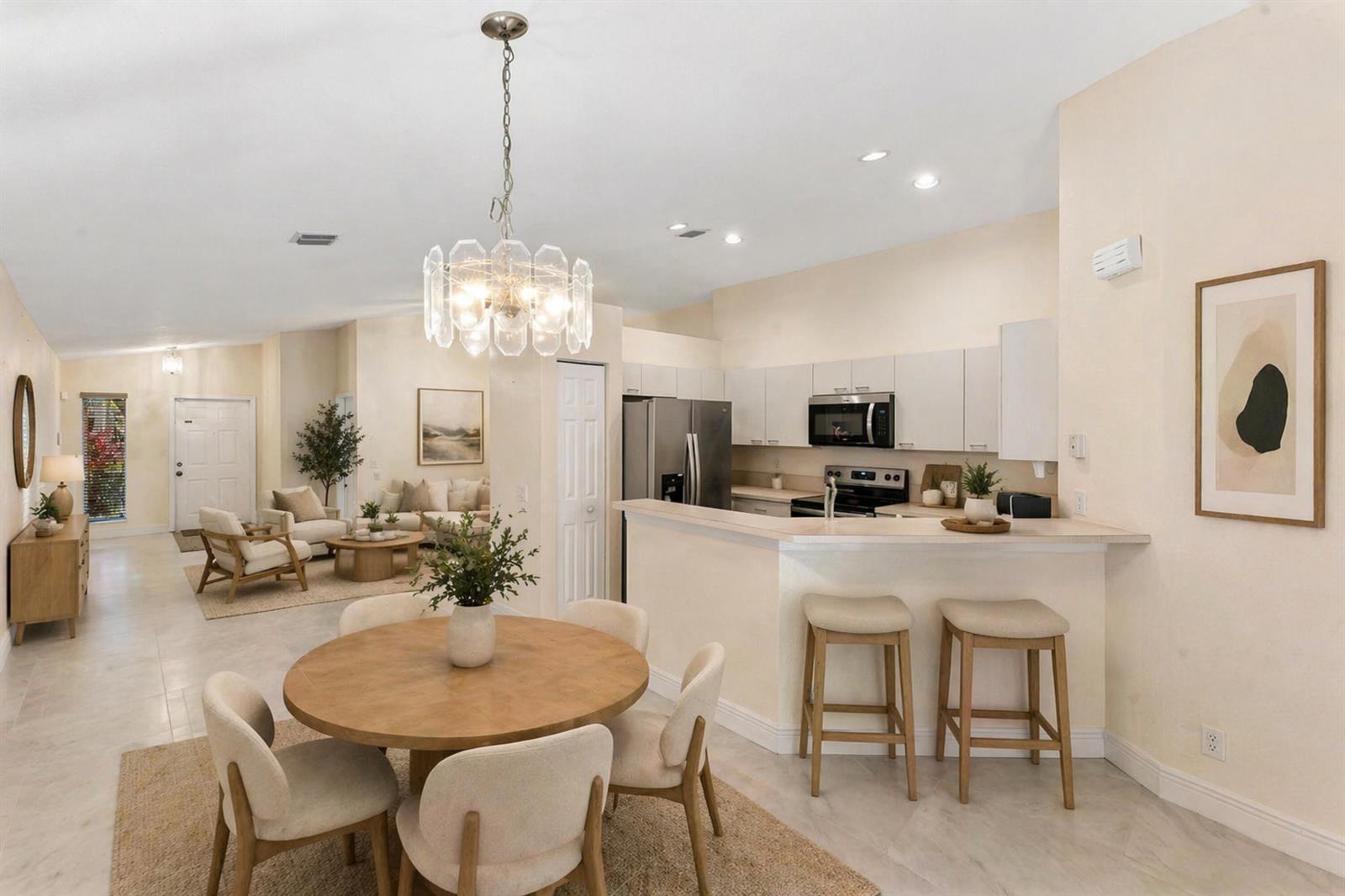 An open-concept kitchen and dining area features a round wooden table, bar stools, and cabinetry — 1353 Canary Island Drive, Weston FL 33327, WESTON, FL