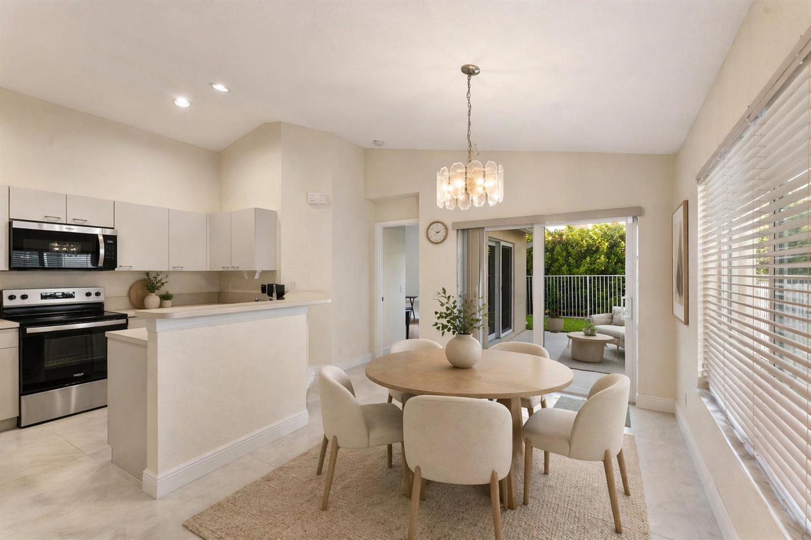 A dining area with a round table and chairs sits adjacent to a white kitchen — 1353 Canary Island Drive, Weston FL 33327, WESTON, FL