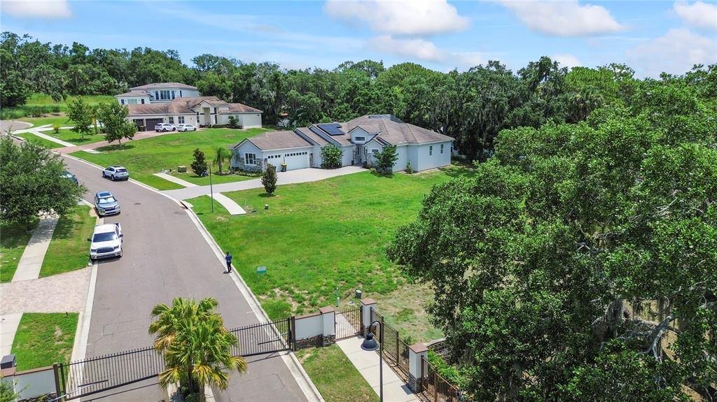 An aerial view shows a suburban street with a gated entrance and several single-family homes — 1825 MOORINGS COURT LOT 14, CLERMONT, FL