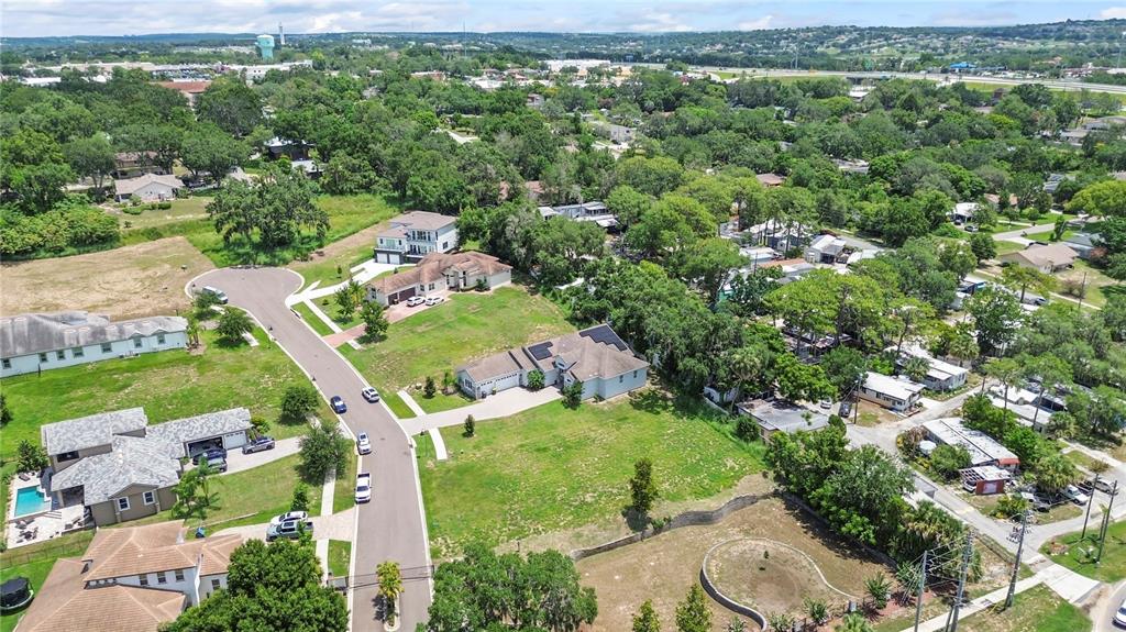 An aerial view shows suburban houses, green lawns, and trees along a paved residential street — 1825 MOORINGS COURT LOT 14, CLERMONT, FL
