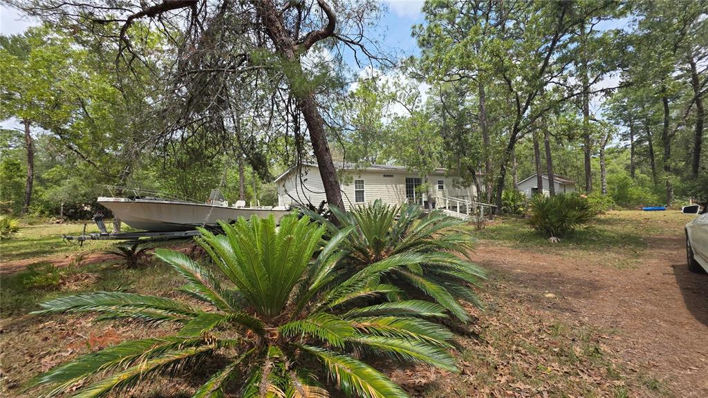 A manufactured home sits in a wooded lot with a boat parked in the yard — 5719 W STOCKHOLM LANE, DUNNELLON, FL