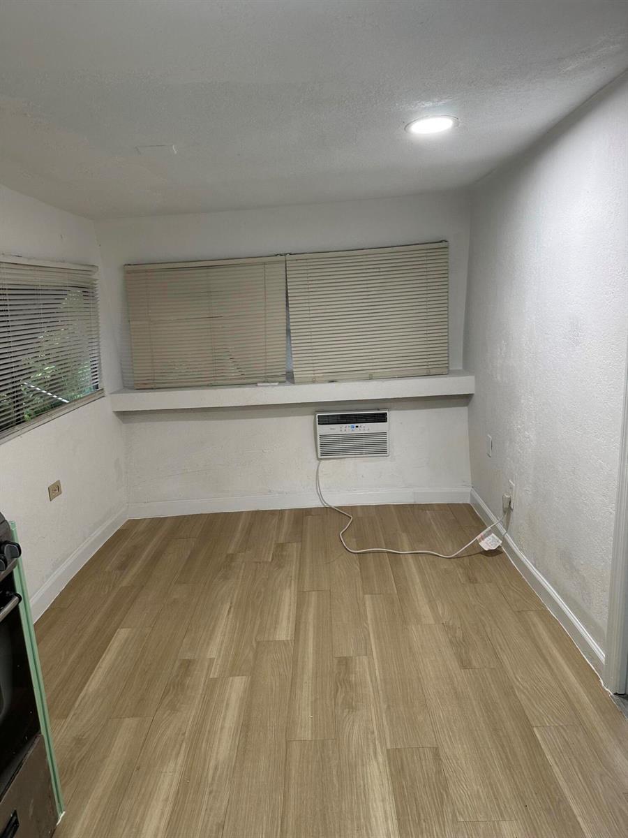 An empty room features light wood-look flooring, white walls, horizontal blinds, and a wall-mounted air conditioner — 4361 Davis Road # 3, Lake Worth FL 33461, LAKE WORTH, FL