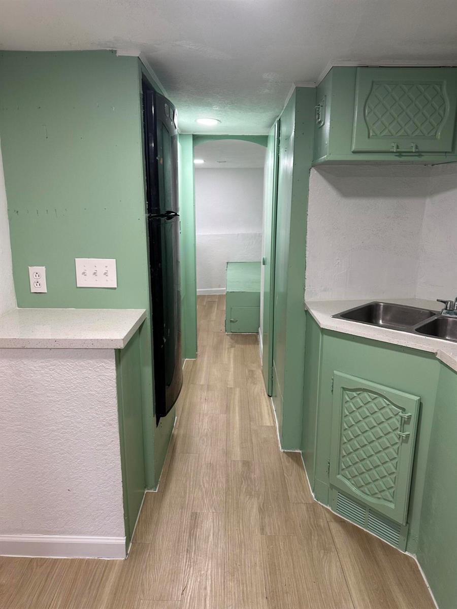 A narrow kitchen features green cabinets, a black refrigerator, and light wood-look flooring — 4361 Davis Road # 3, Lake Worth FL 33461, LAKE WORTH, FL