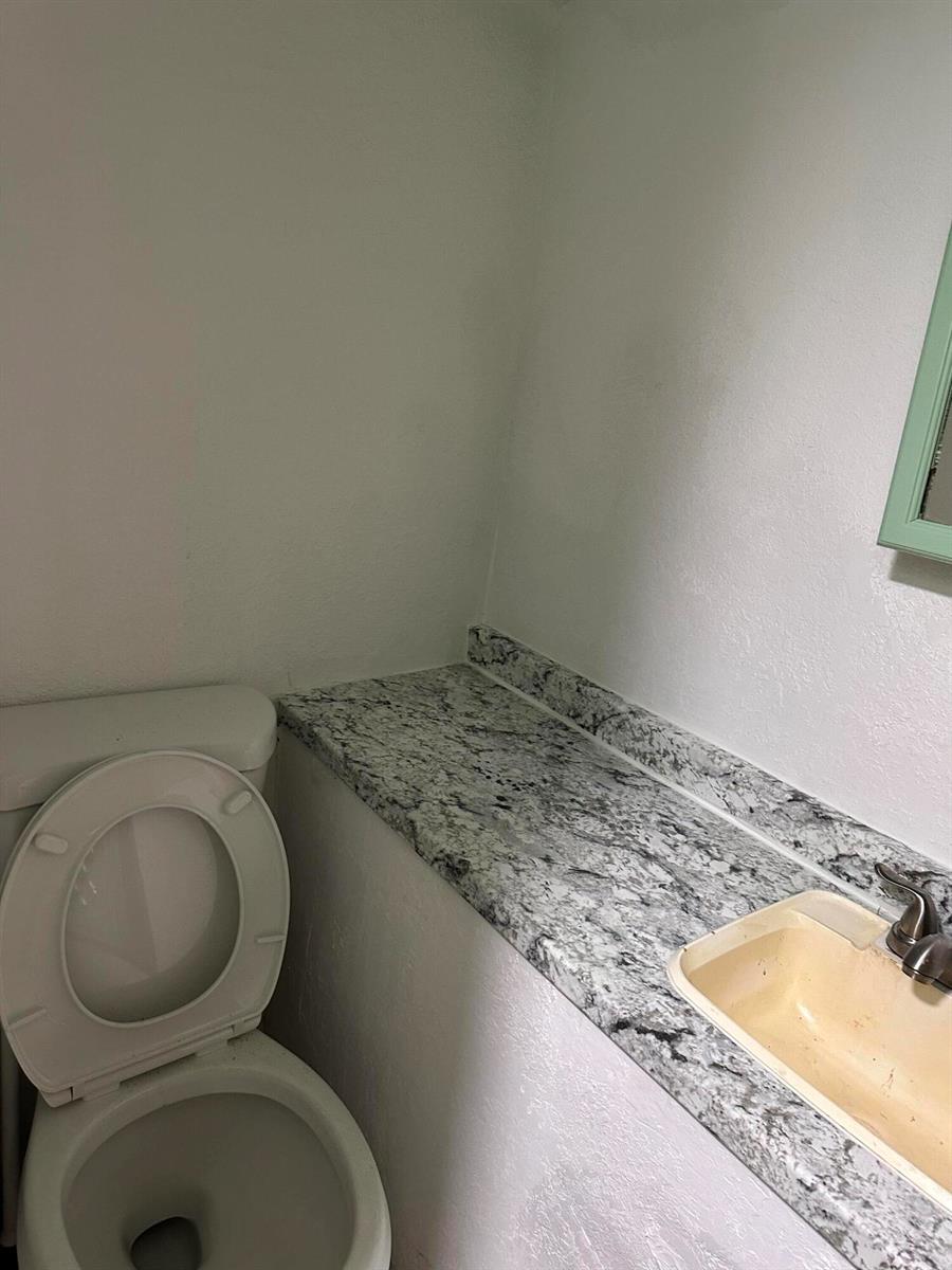 A bathroom features a toilet next to a vanity with a granite countertop and sink — 4361 Davis Road # 3, Lake Worth FL 33461, LAKE WORTH, FL