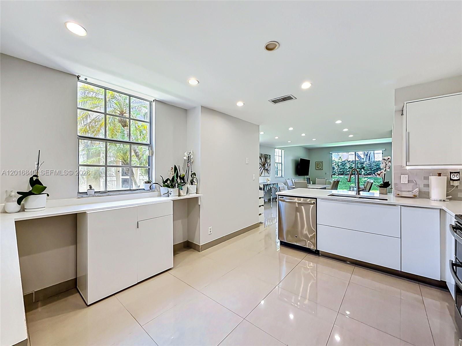 A modern kitchen features white cabinetry, stainless steel appliances, and large floor tiles — 952 Sevilla Cir, Weston FL 33326, WESTON, FL