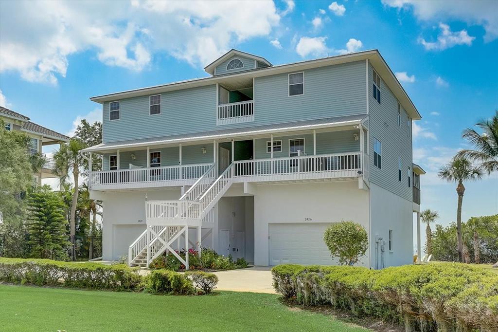 A light blue, elevated three-story house with a white garage base and a front staircase — 2424 BAY DRIVE UNIT 2424/2426, BRADENTON, FL