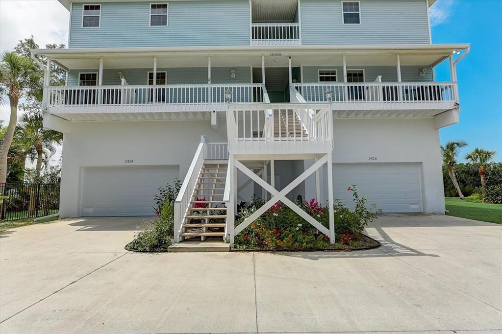 An elevated two-story house features a central staircase leading to a porch above two garages — 2424 BAY DRIVE UNIT 2424/2426, BRADENTON, FL