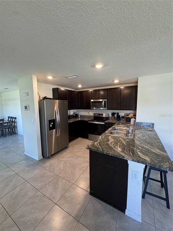 A kitchen features dark wood cabinets, stainless steel appliances, and a granite-topped island — 4234 AUTUMN FOG COURT, PALMETTO, FL