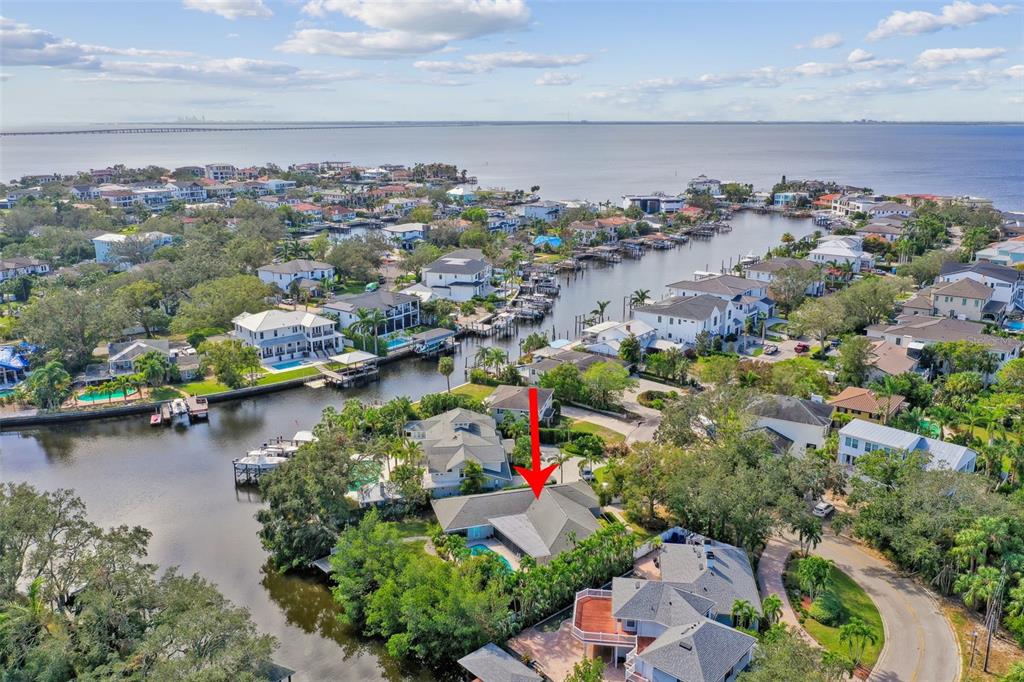 An aerial view shows a waterfront house with a pool and a red arrow pointing down — 5104 W SAN JOSE STREET, TAMPA, FL