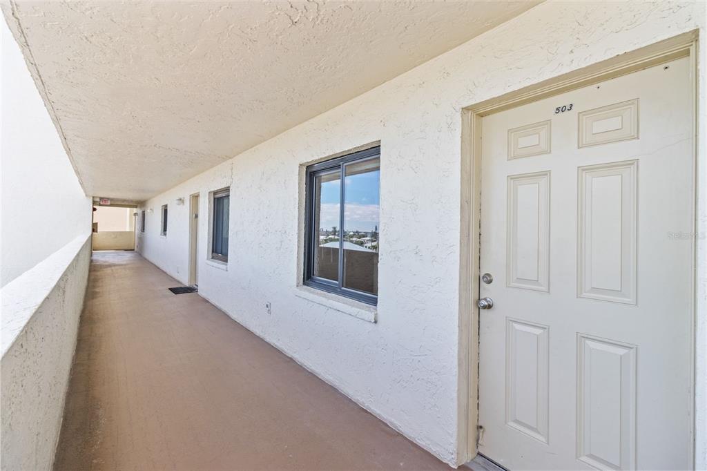 An exterior hallway with a white door labeled 503 and a window on a building — 14950 GULF BOULEVARD UNIT 503, MADEIRA BEACH, FL