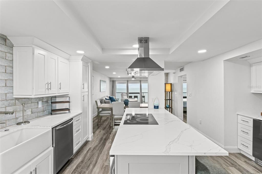 A modern kitchen with white cabinets, a marble-topped island, and a view of the ocean — 14950 GULF BOULEVARD UNIT 503, MADEIRA BEACH, FL