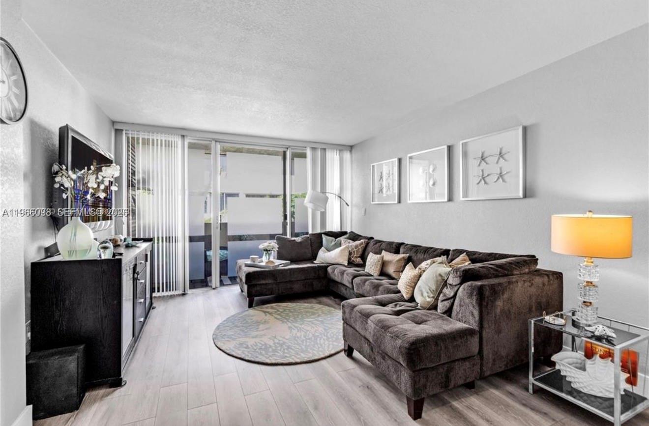 A living room features a large gray sectional sofa, a round rug, and a glass side table — 830 NW 87th Ave # 303, Miami FL 33172, MIAMI, FL